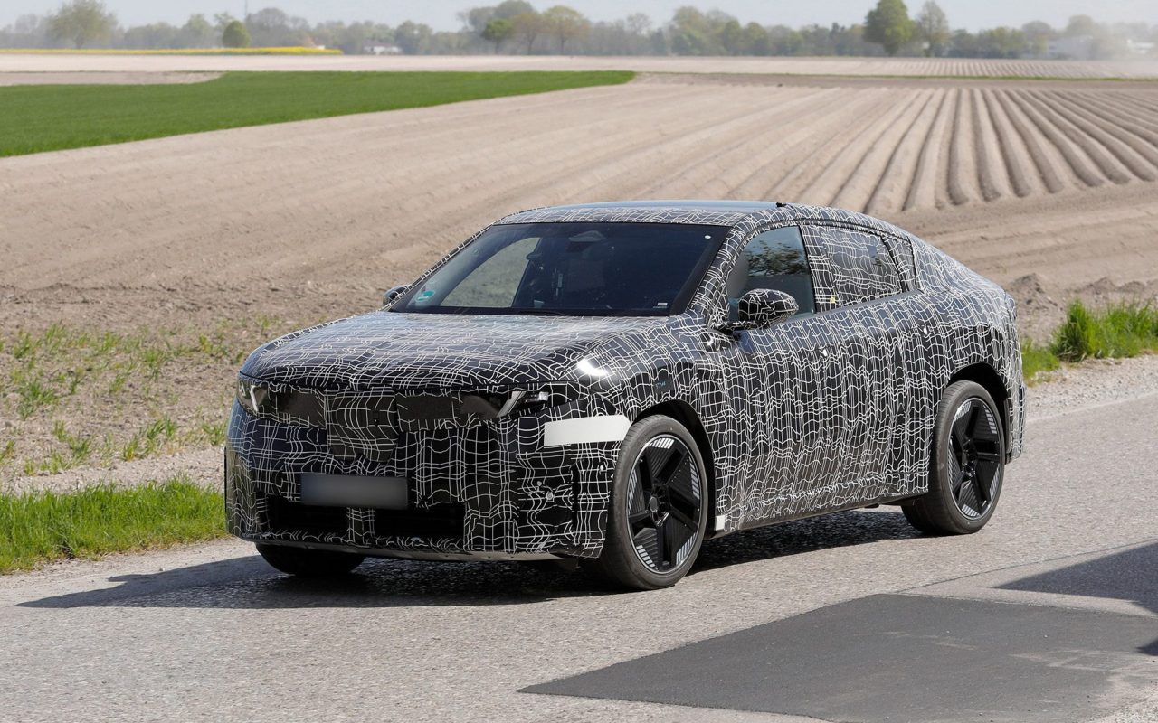 Tamamen elektrikli BMW iX4 SUV coupe prototipi, 2026 test sürüşünde siyah-beyaz kamuflajla çekilmiş araç fotoğrafı